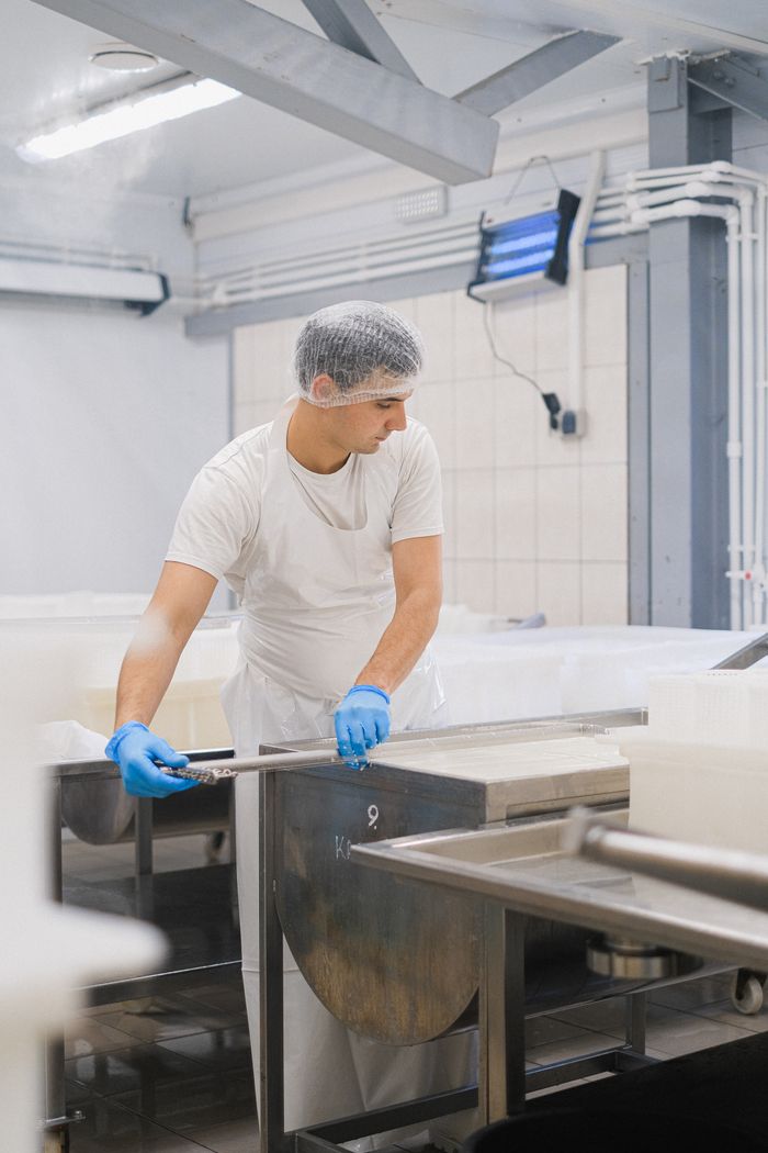 services-02 Man in a protective suit managing machinery in a dairy processing facility.