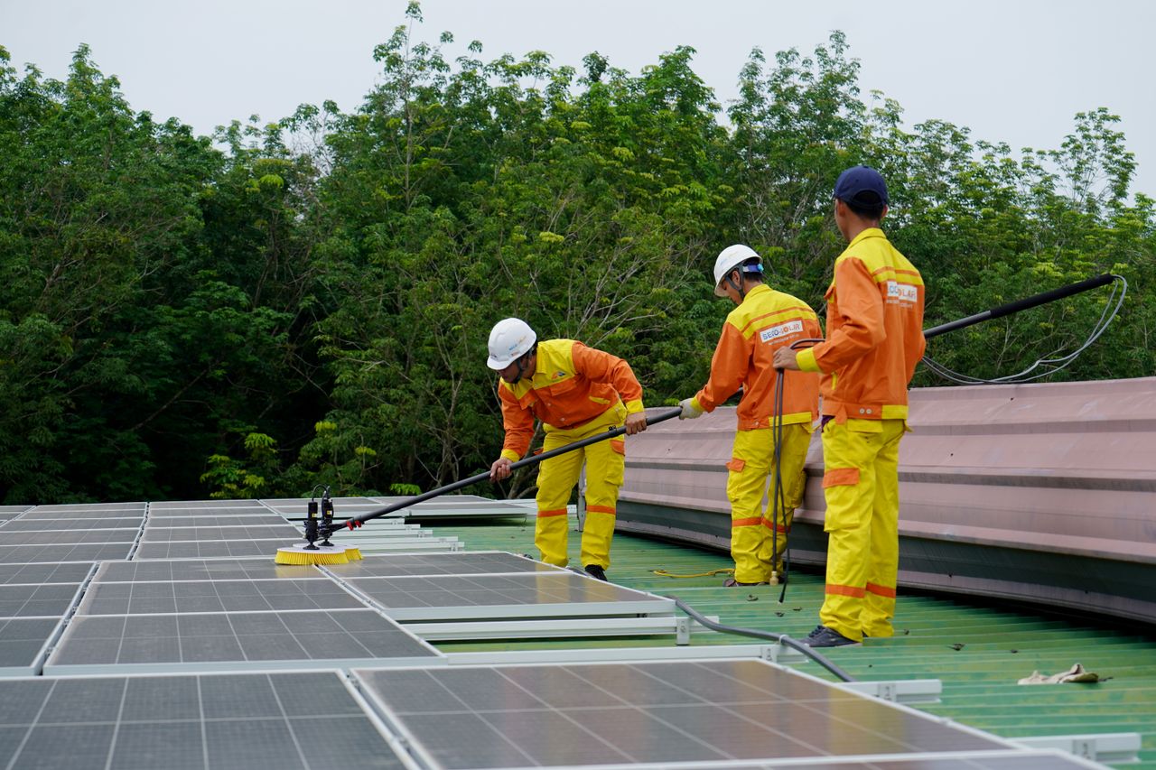 heros-img Three technicians in uniforms and hardhats clean rooftop solar panels in a renewable energy project.